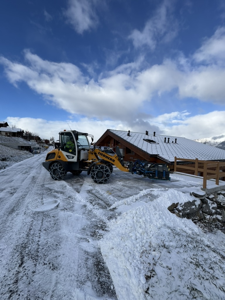 Chargeuse Liebherr déneigeant l'accès d'un chalet